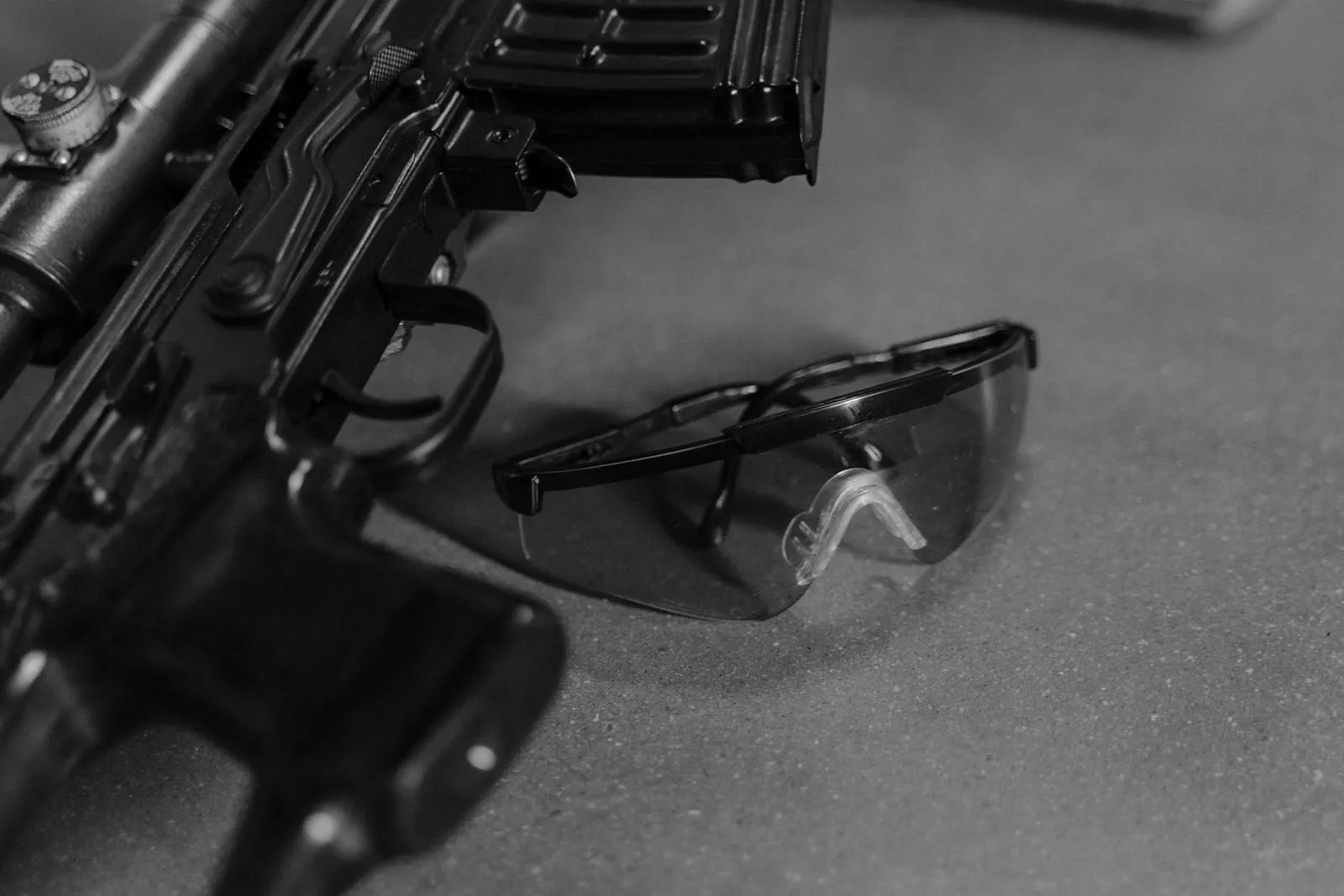 Black and white close-up of an AR-15 rifle with safety glasses